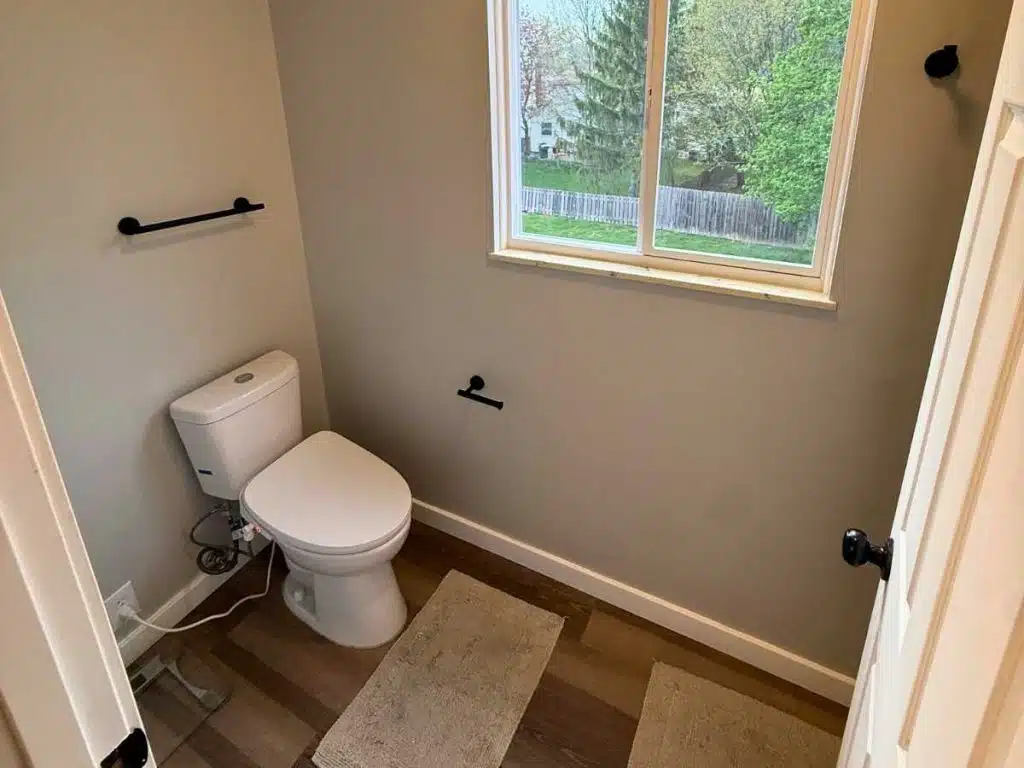 After - repaired bathroom with smooth painted walls new toilet fixtures and clean finished trim around the window