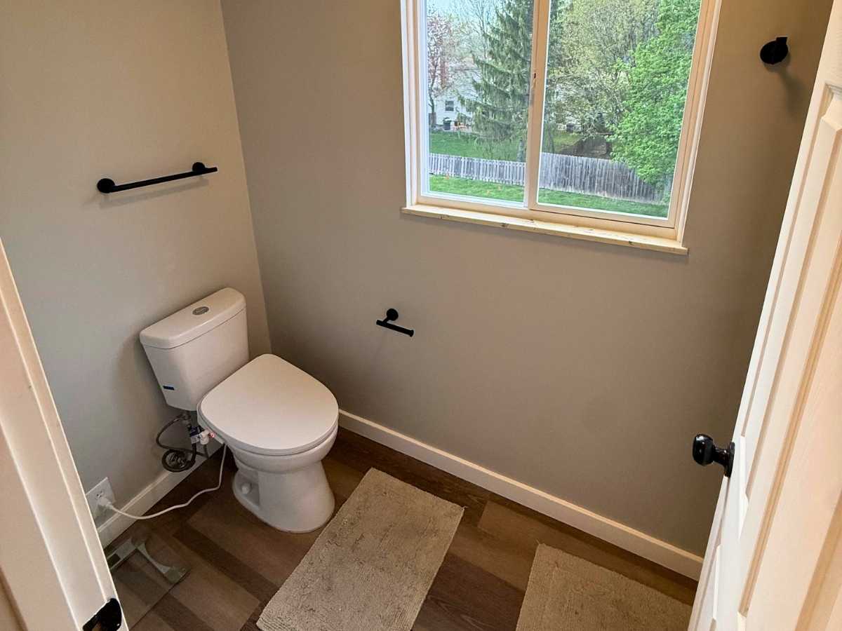 After - repaired bathroom with smooth painted walls new toilet fixtures and clean finished trim around the window