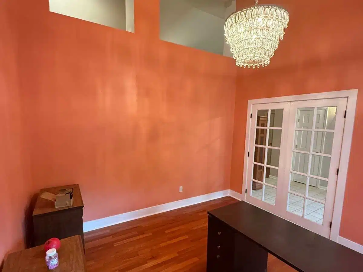 After - same room with smooth peach painted walls white trim hardwood floors and French doors finished renovation