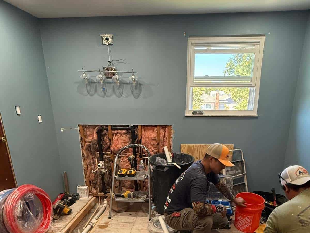 Bathroom under renovation - exposed plumbing - removed vanity wall - remodeling crew working - Columbus Ohio