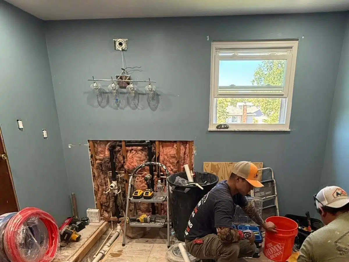 Bathroom under renovation - exposed plumbing - removed vanity wall - remodeling crew working - Columbus Ohio