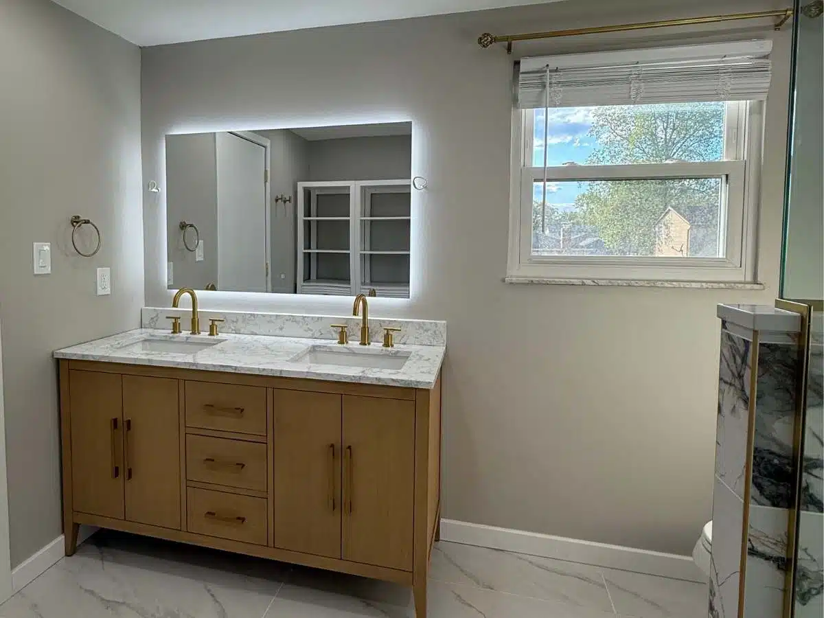 Finished bathroom remodel - wood vanity - backlit mirror - gold fixtures - marble look flooring - Columbus Ohio