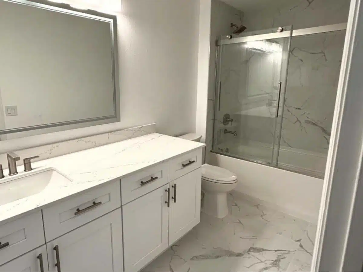 Remodeled bathroom after renovation - white shaker vanity - marble look surfaces - bathtub shower glass door - modern finishes - Columbus Ohio