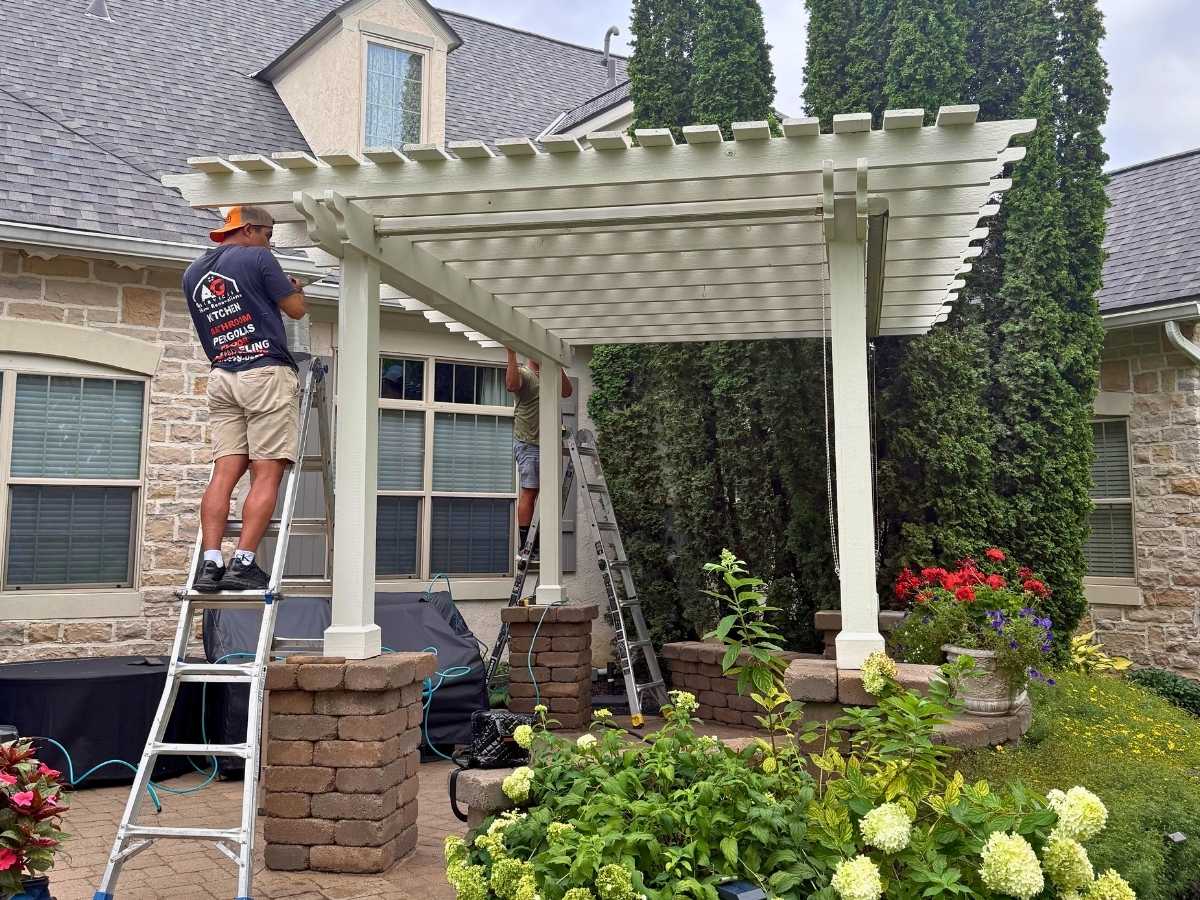 workers installing white pergola over patio residential backyard columbus ohio home improvement project